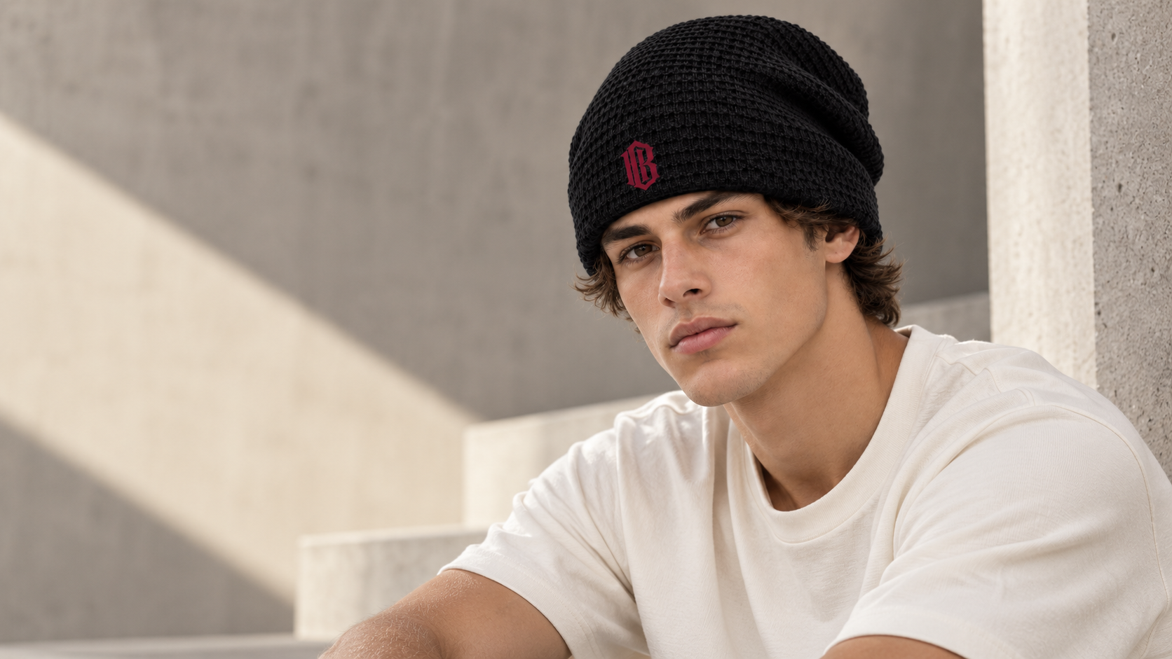 Gothic B Beanie, worn on concrete steps